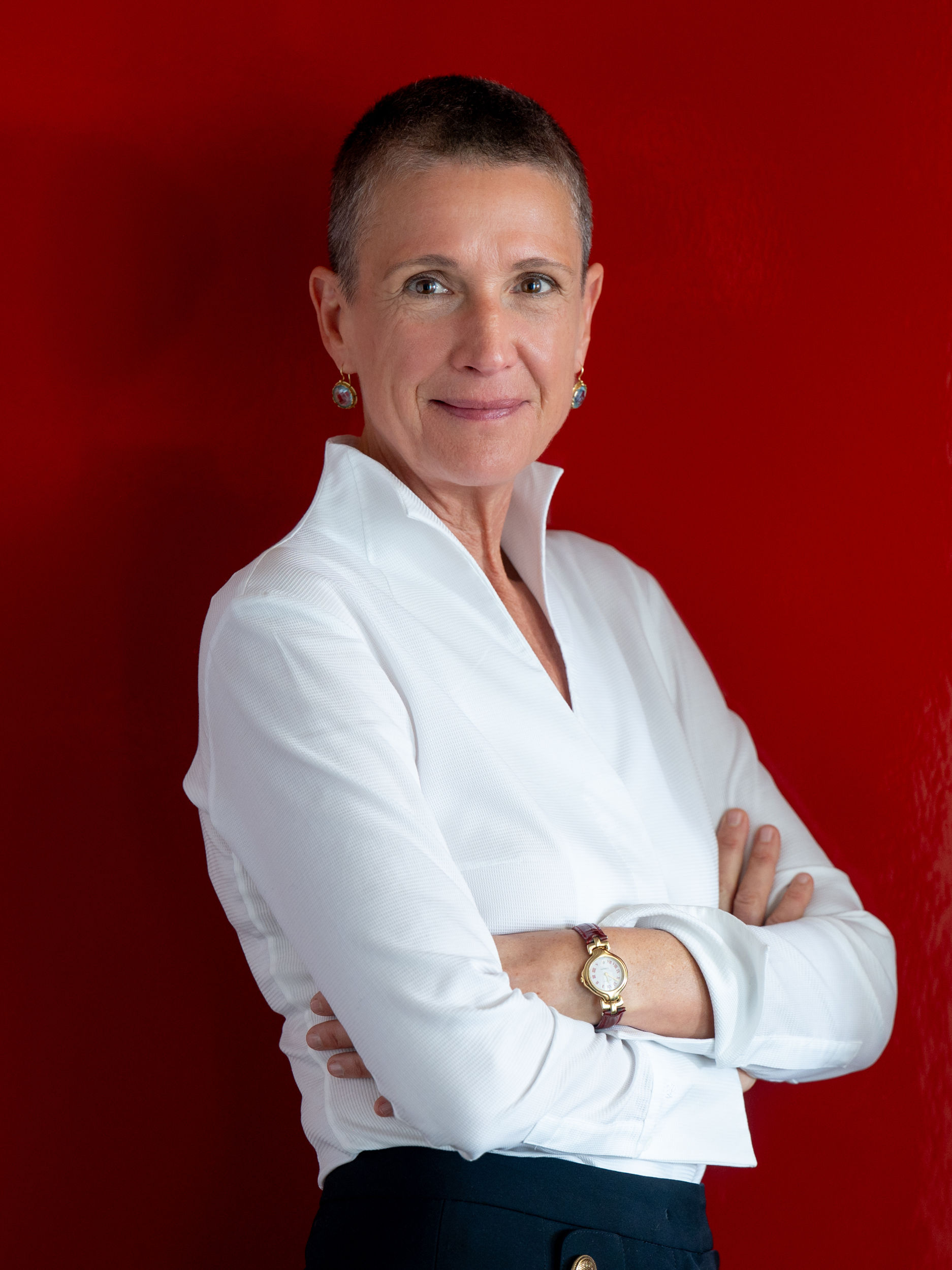 Sabine fb Lueder | LUEDER INTERNATIONAL Sabine fb Lueder in weißer Bluse vor einer roten Wand